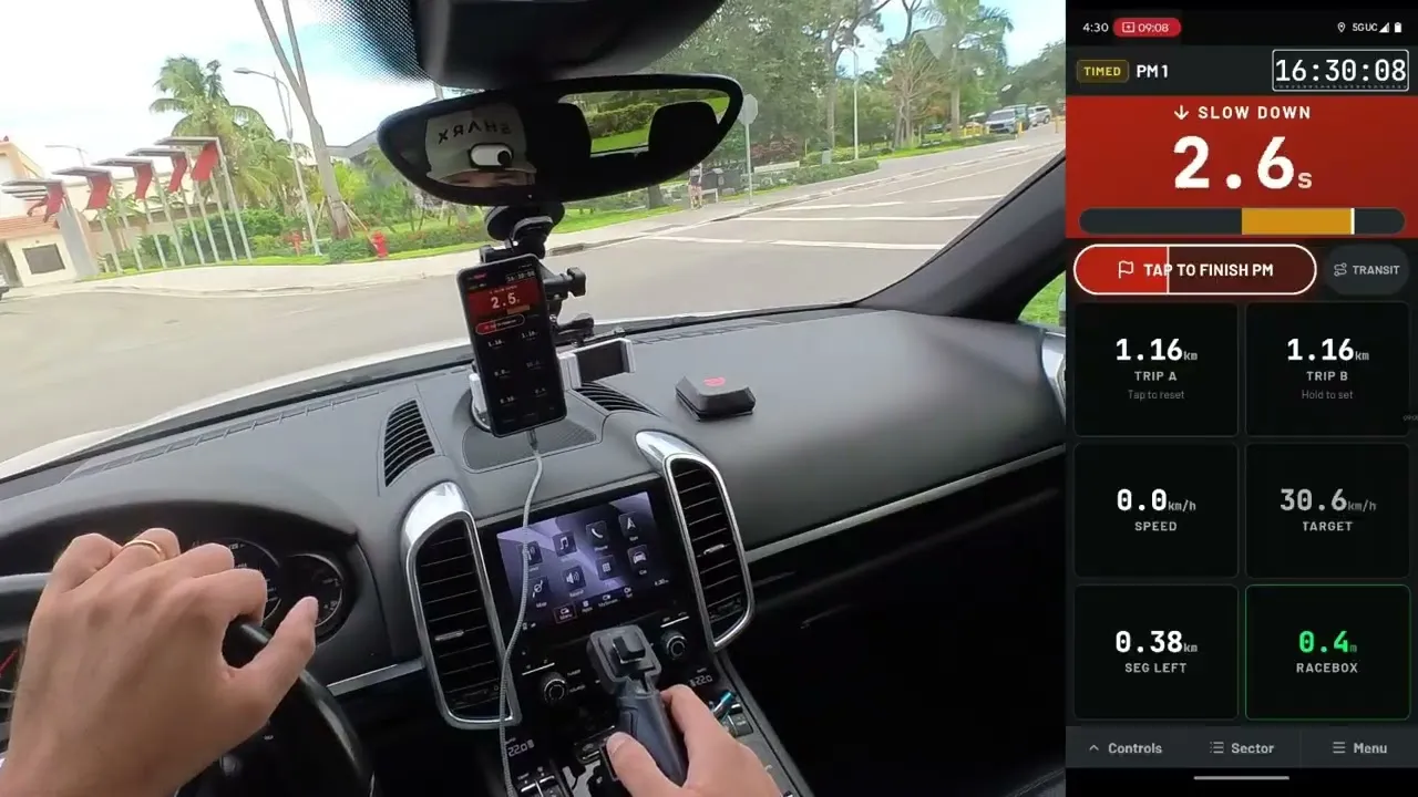 In auto: un telefono sul cruscotto con la prova di media di Crono107, la mano del navigatore sul telecomando e un RaceBox Mini sul cruscotto, con la schermata dell’app ingrandita accanto