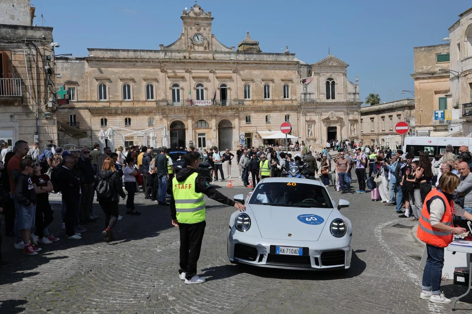 L’auto 60 arriva in una piazza affollata davanti a un palazzo barocco, con un commissario che la fa entrare